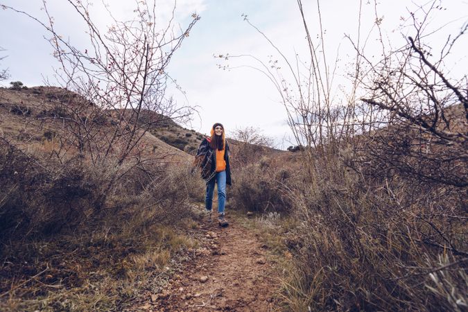 Hiker with backpack walking along pathway in autumn forest