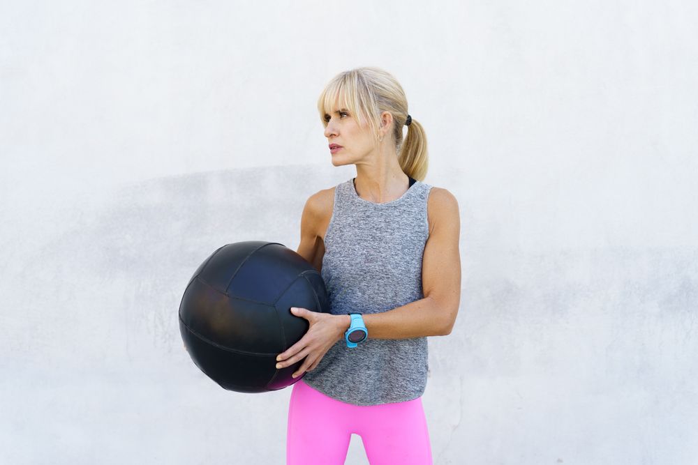 Healthy woman in pink leggings with medicine ball