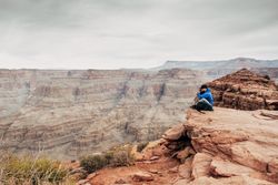 Male having rest on edge of rock and relishing beverage