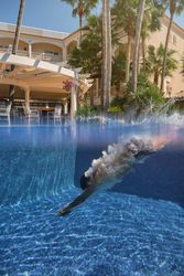 Unrecognizable person jumping in pool in tropical resort