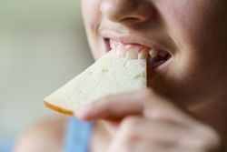 Girl biting into cheese slice