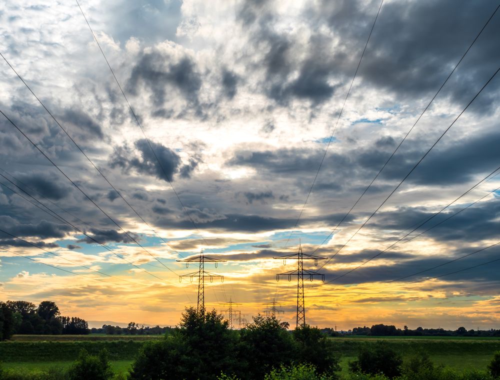 Power lines recede into the distance against the backdrop of a colorful sunset sky