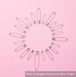 Safety pins in a circle shape over pink background 4dELAb