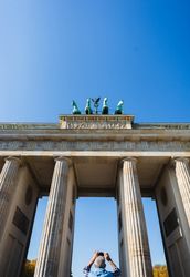 Brandenburg Gate in Berlin, Germany, being photographed by older sightseeing tourist man from below