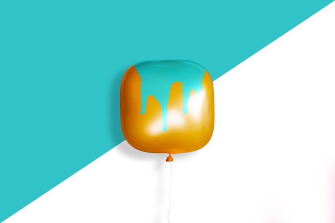 Square orange balloon with paint dripping on it on a blue background