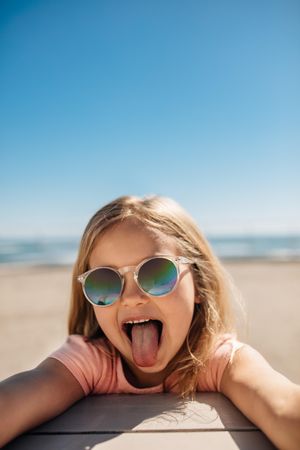 Young girl making funny faces at the beach on a summer day