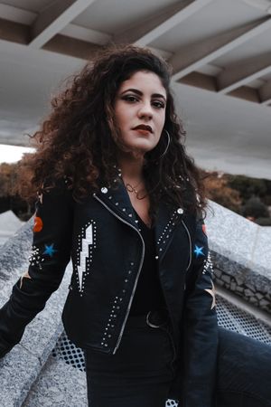 Modern woman in jacket and jeans standing in city