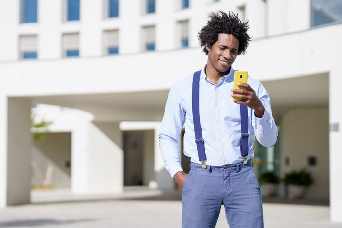 Smiling man looking at phone screen outside