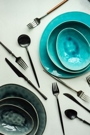 Top view of full teal table setting surrounded with silverware with on grey counter