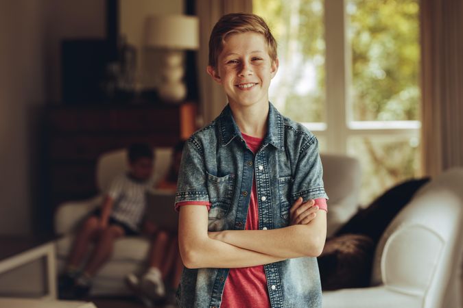Portrait of a smiling boy standing at home with arms crossed