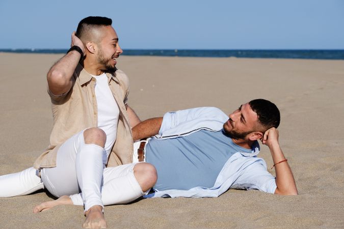 Affectionate gay couple relaxing on beach