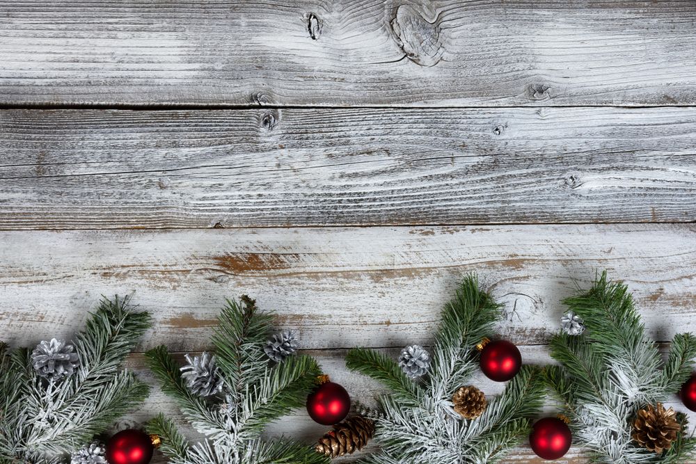 snow covered fir tree branches with seasonal decorations on rustic wood for the winter holiday