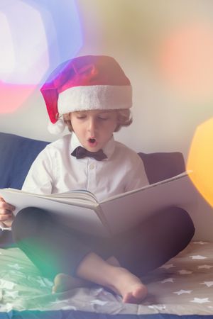 Excited boy in Santa hat reading book