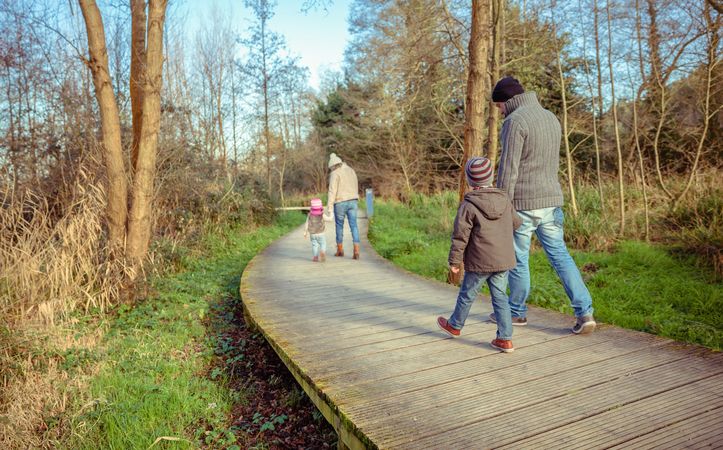 Parents walking with their young children along trail in forest