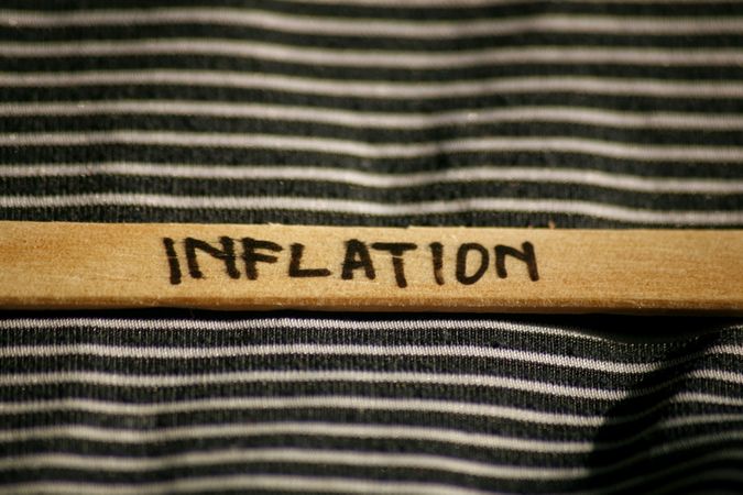 Close up of the word “inflation” written on wooden stick laying on striped fabric