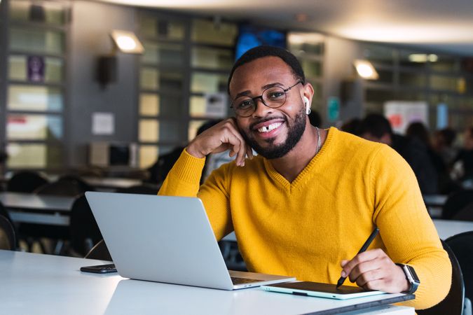 Smiling Black man working on laptop with tablet