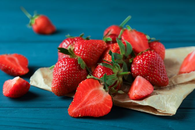 Fresh strawberries and parchment on wooden background, space for text and closeup. Summer sweet fruits and berries