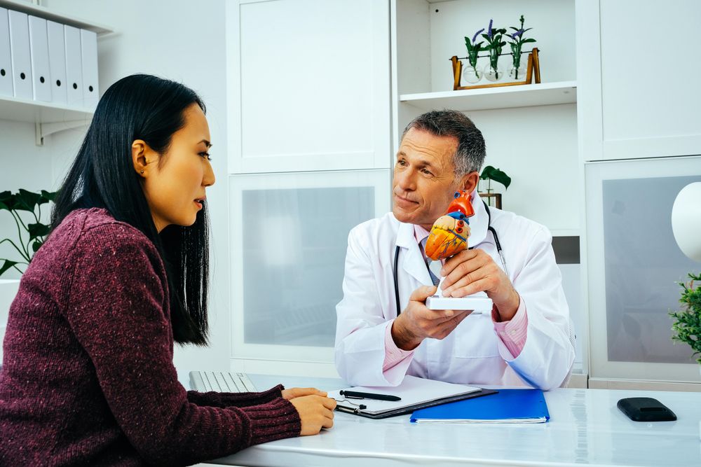 Male doctor with serious female patient consulting about heart structure