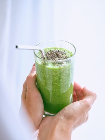 Crop person holding glass of healthy beverage