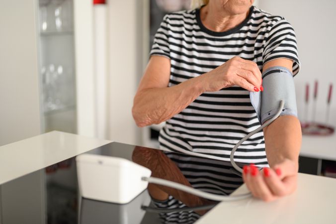 Crop of older woman measuring blood pressure