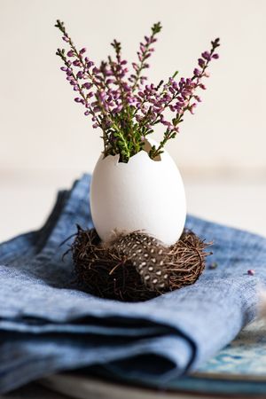 Easter table setting with heather in decorative egg on blue napkin