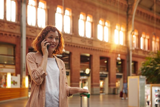 Red haired young woman using smartphone at station