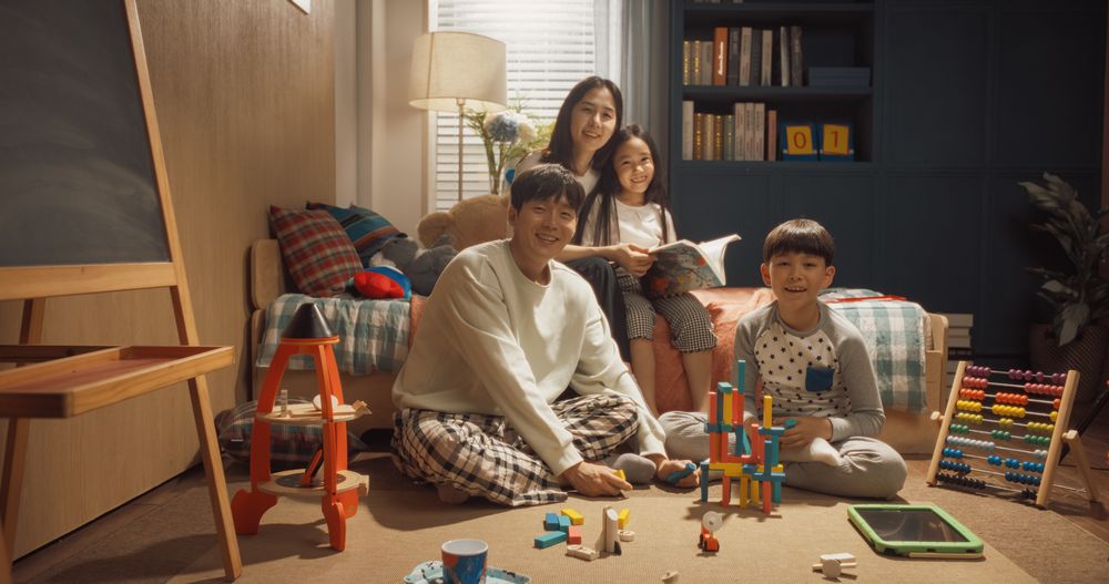 Happy Korean Family Portrait with Adults And Kids Looking at Camera and Smiling in Children's Room.