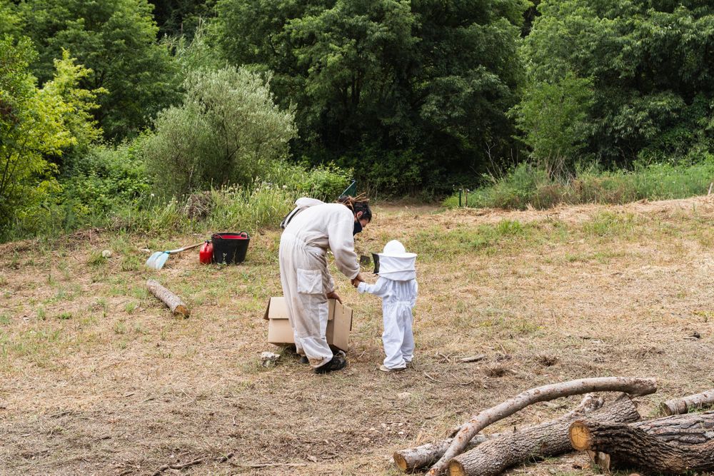 Unrecognizable beekeeper and child in costumes in countryside