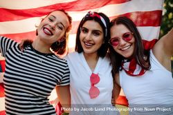 Three female friends smiling with American flag 56eKN0