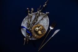 Top view of blue table and bird's nest on grey table for Easter table setting