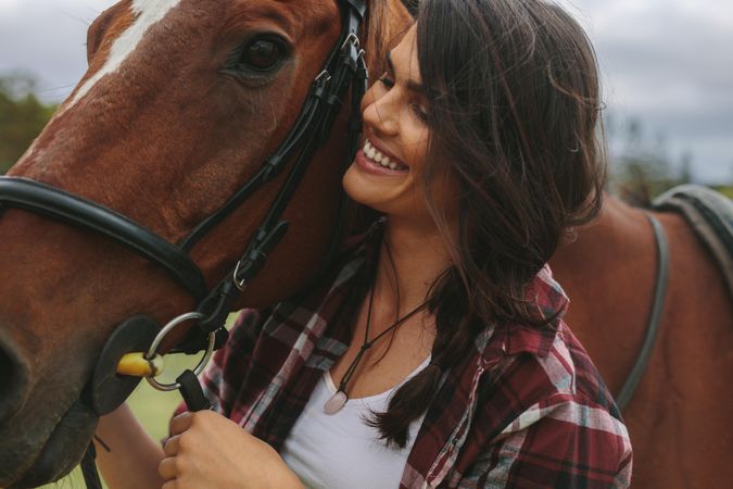 Close up of happy equestrian woman with a brown horse