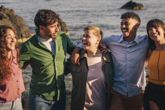 Group of diverse young friends laughing and walking on the beach together