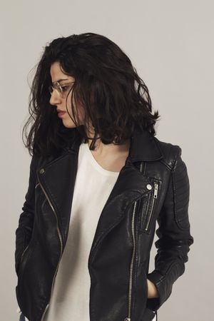 Serious pensive young female wearing leather jacket in studio