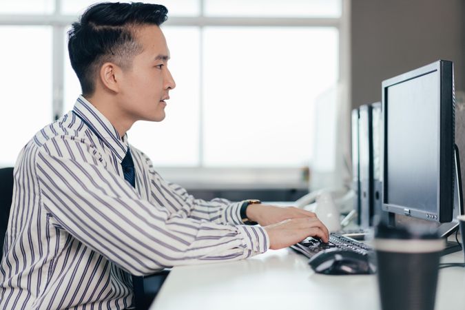 Asian male employee at desk in the office