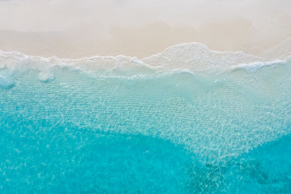 Aerial shot of waves coming in on a tropical beach