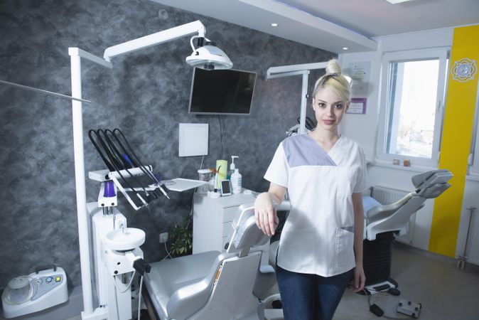 Blonde dentist in with her arm on the dentist chair