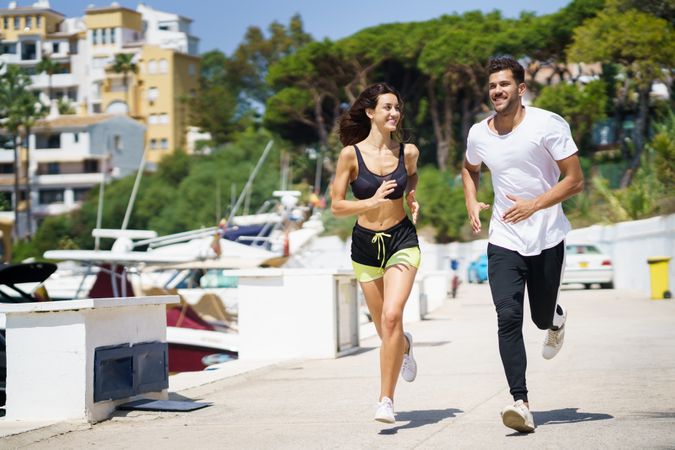 Happy man and woman jogging on pier