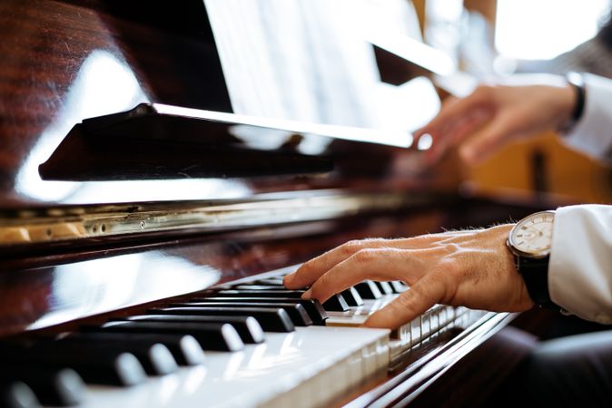 Crop male hands playing piano