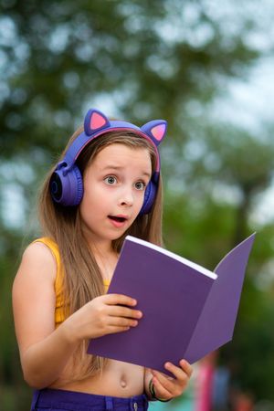 Preteen school girl with book on bench in park