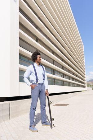 Man outside his office with skateboard, vertical