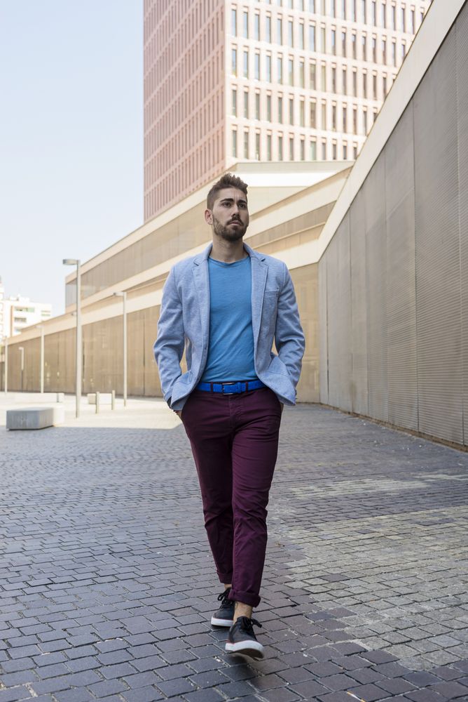 Man in blazer casually walking on street with hands in pockets