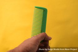 Hand with green hair comb with yellow background 5zrElm
