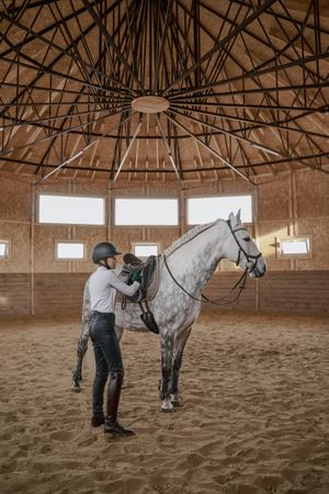 Rider with dapple gray horse in round arena