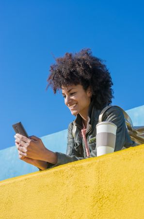 Black woman with afro hair leaning against brightly colored wall