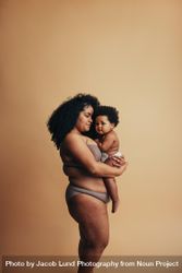 Woman with long curly hair holding her cute baby with afro 5aAyG5
