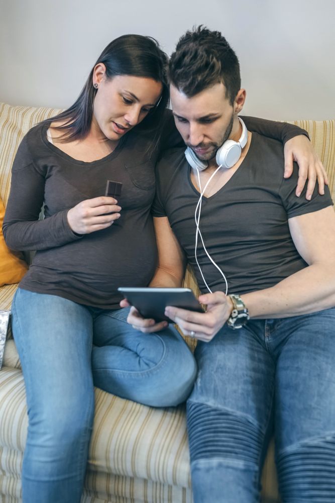 Pregnant with her partner looking at the tablet