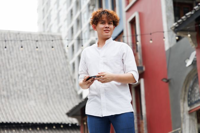Asian man holding mobile phone standing in the city