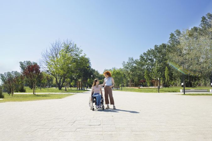 Red haired woman standing next to her friend in a wheelchair