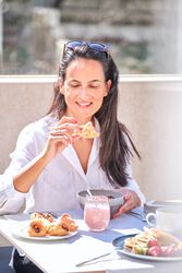 Positive woman eating delicious croissant for breakfast in sunny