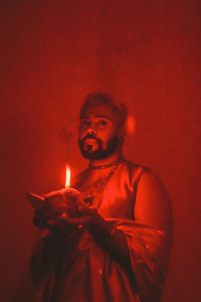 Portrait of Indian man holding a diya in red lit studio